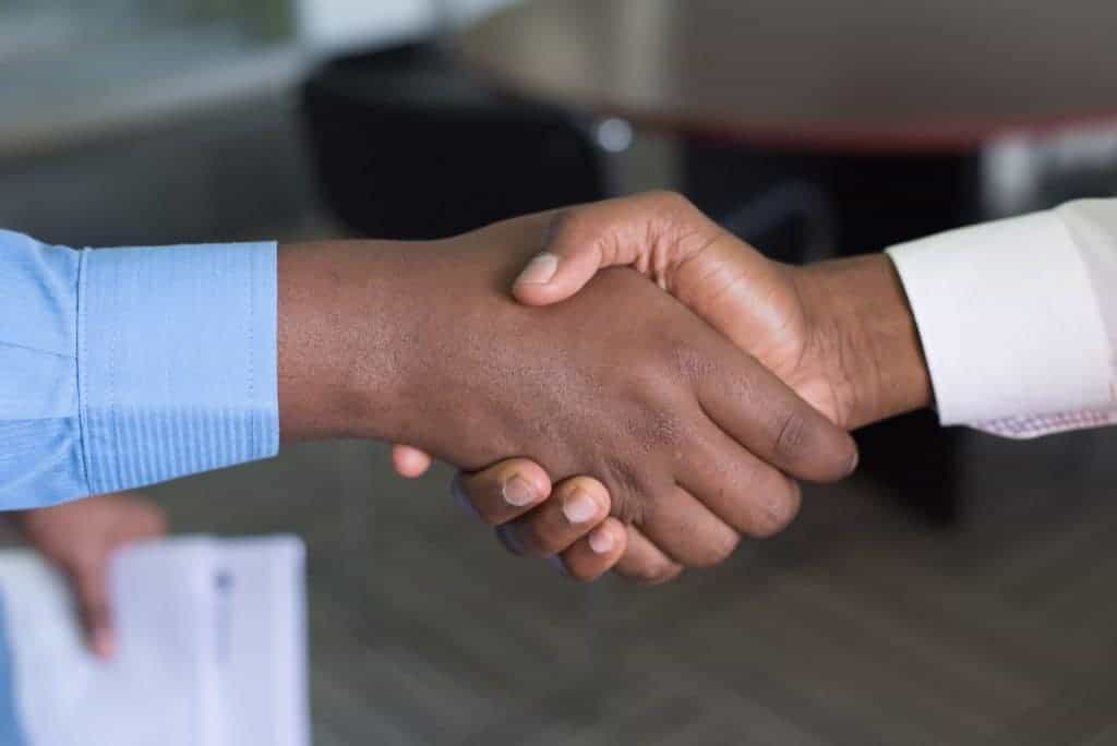 Zwei Geschäftsleute in Hemd geben sich die Hände, weil sie einen Deal abgeschlossen haben.